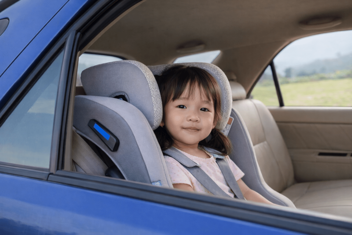Petite fille installée dans un siège auto avec harnais, sur la banquette arrière d'une voiture
