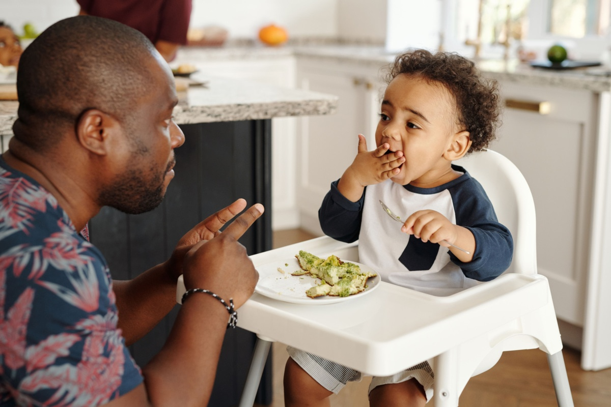 Bébé mangeant son repas dans sa chaise haute avec son papa