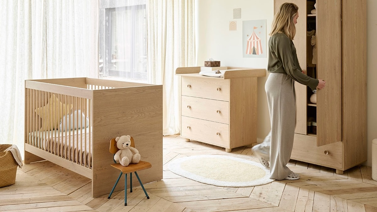 Chambre de bébé aménagée avec un lit à barreaux, une commode et une armoire de rangement en bois