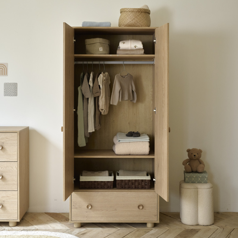 Armoire en bois ouverte avec penderie, étagères et tiroir pour ranger les vêtements de bébé