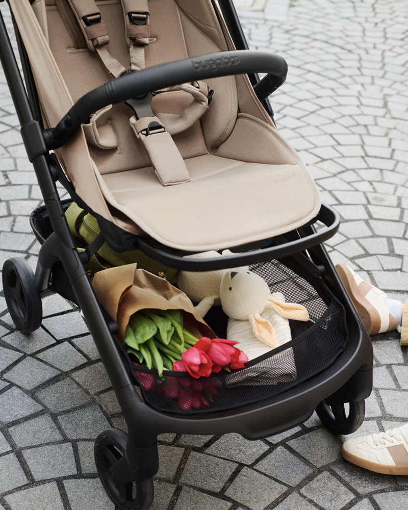 Gros plan sur le panier de rangement de la poussette Bugaboo Butterfly 2, contenant un bouquet de fleurs et une peluche