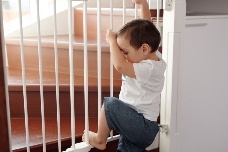 Jeune enfant tentant d'escalader une barrière de sécurité devant un escalier