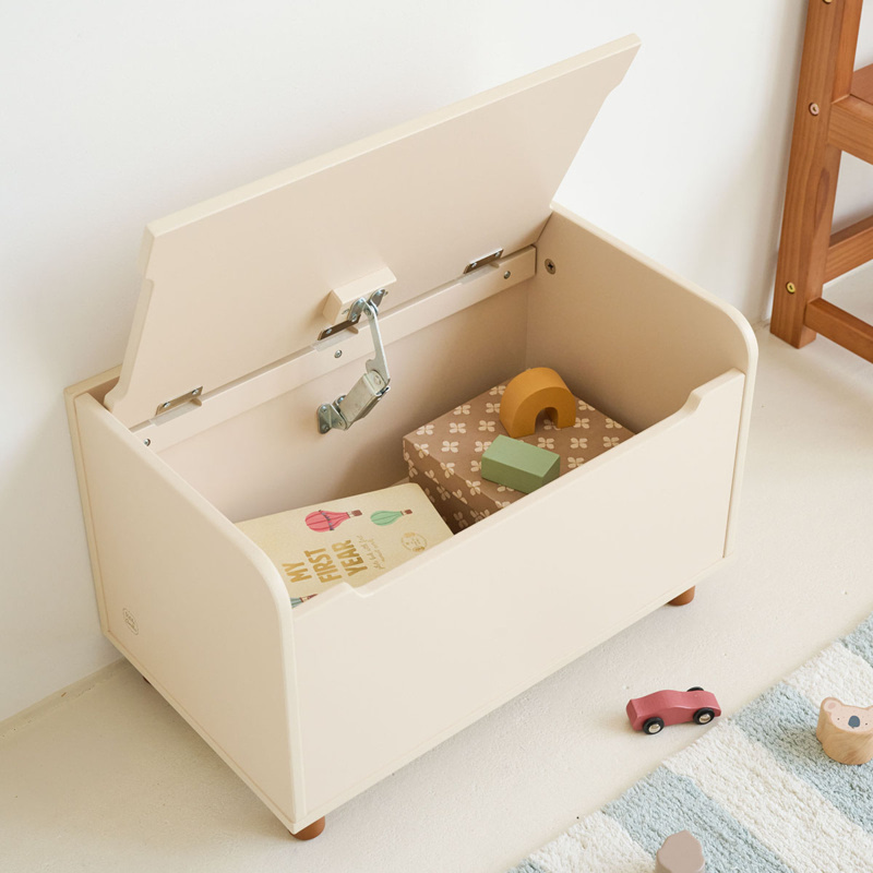 Coffre à jouets blanc ouvert contenant des livres et des jouets en bois