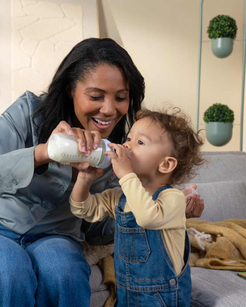 Gros plan d'une maman aidant son enfant à boire un biberon, moment de complicité au quotidien