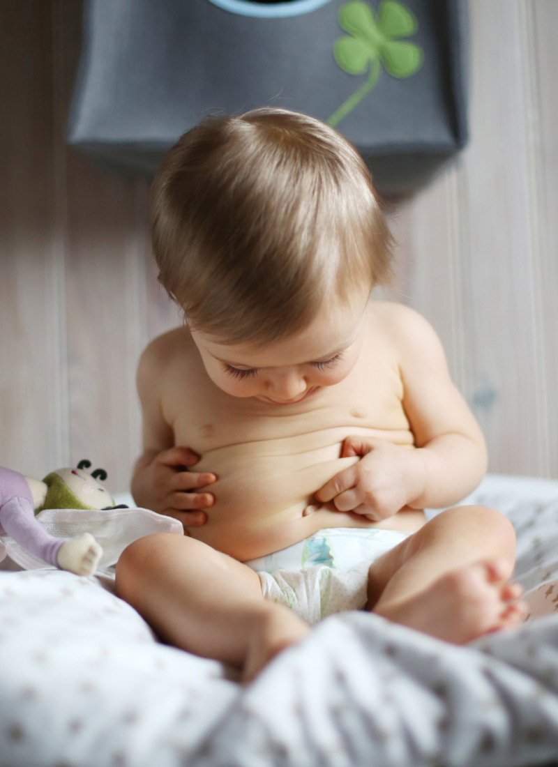 Bébé assis en couche regardant son ventre