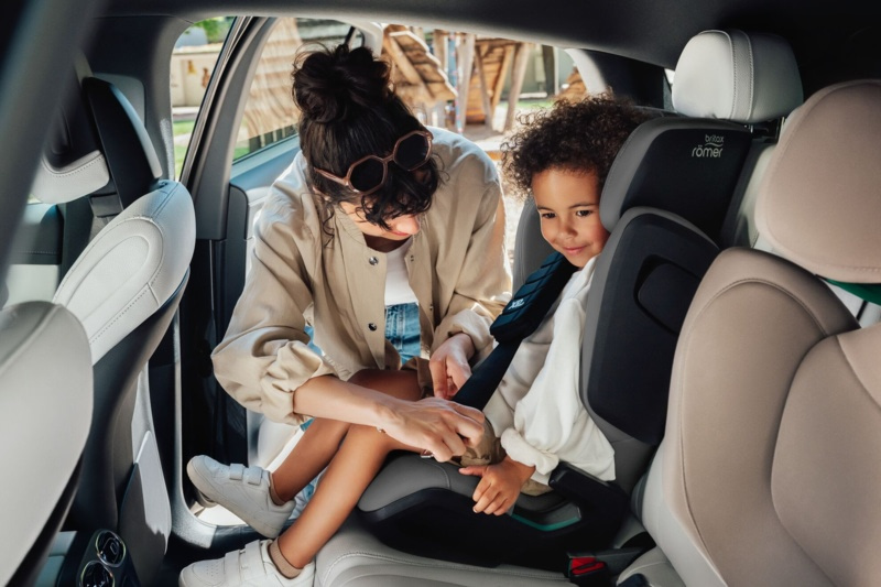 Une maman installe correctement son enfant dans un siège-auto à l'arrière d'une voiture