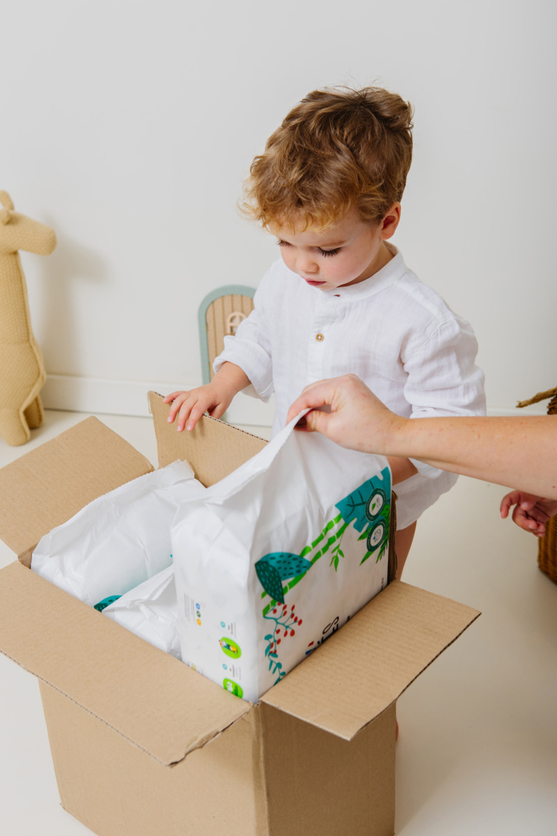 Enfant découvrant un carton de couches avec un adulte