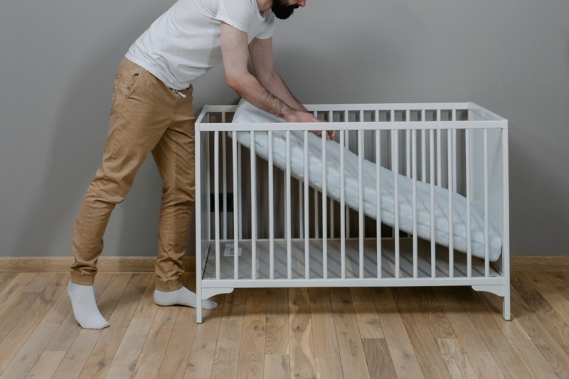 Parent installant un matelas dans un lit bébé