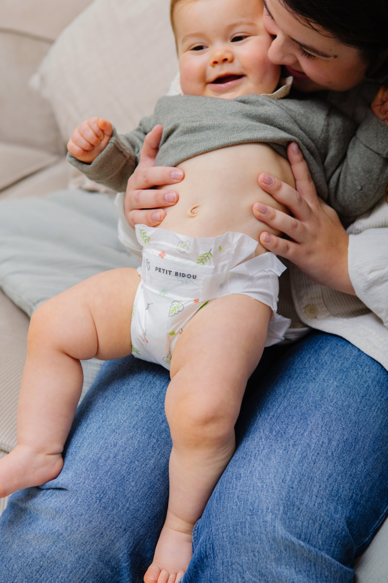 Bébé en couche souriant sur les genoux d'un parent