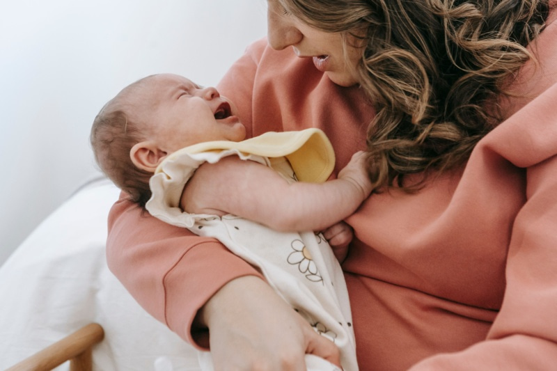 Une maman tient dans ses bras son nourrisson qui pleure