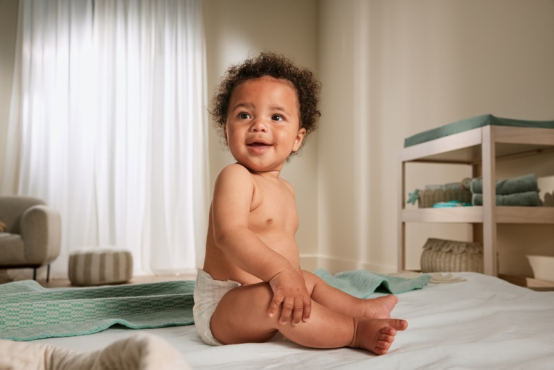 Bébé en couche assis dans une chambre avec une table à langer en arrière-plan
