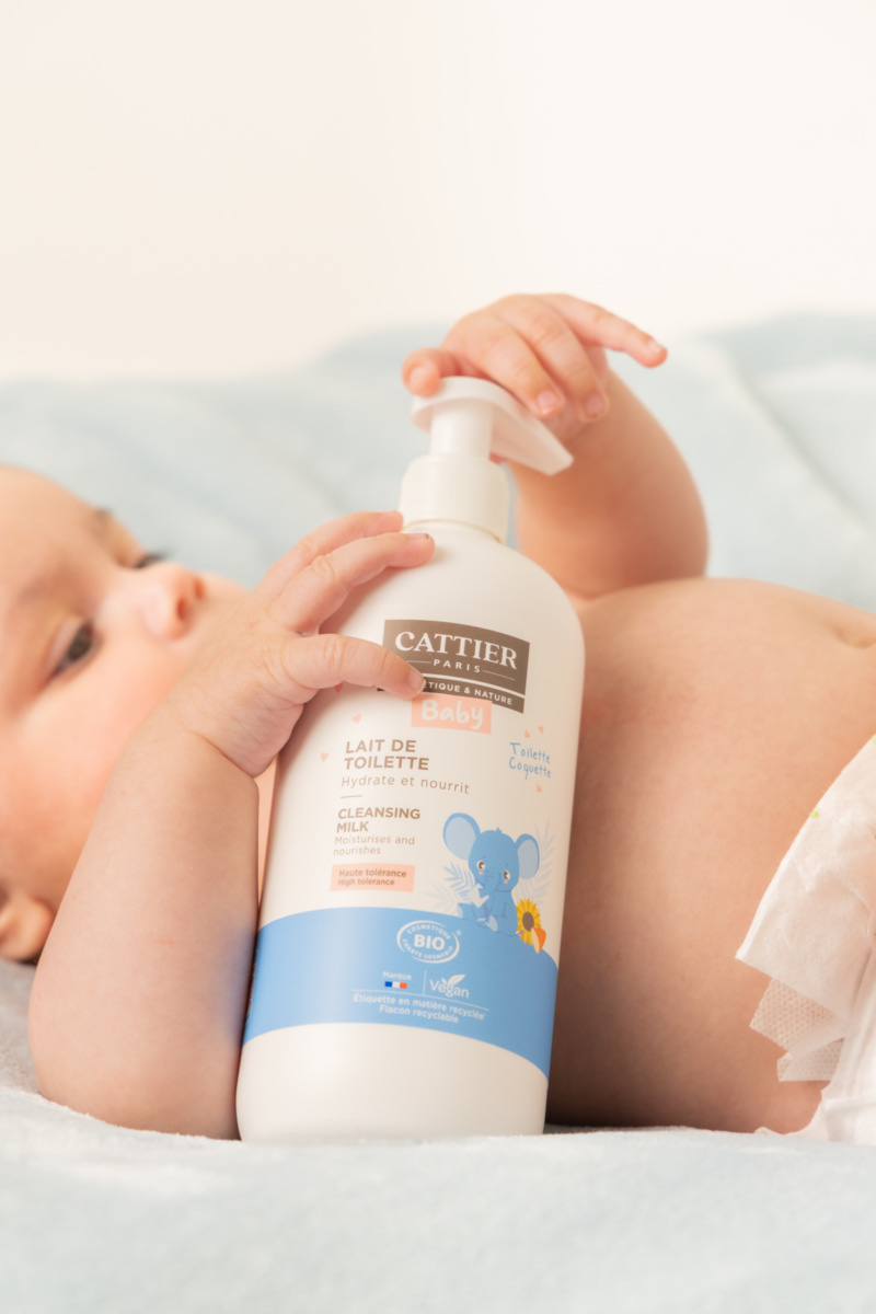 Bébé tenant un flacon de lait de toilette Cattier adapté aux peaux sensibles
