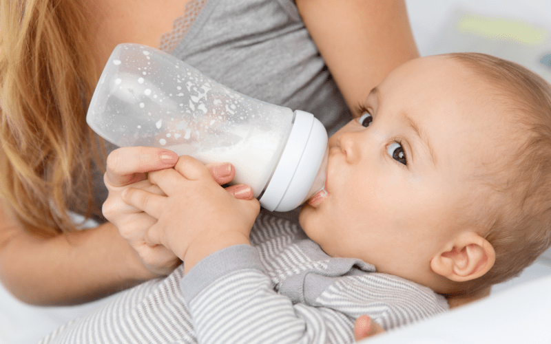 Bébé nourri au biberon de lait infantile dans les bras de sa maman