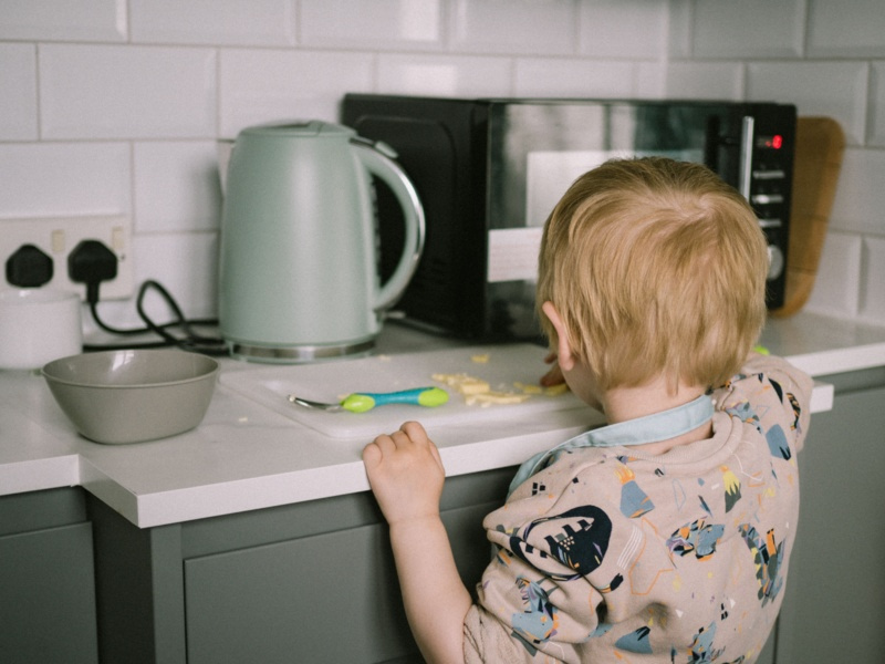 Jeune enfant près d'une bouilloire électrique sur un plan de travail dans une cuisine