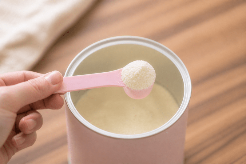 Cuillère doseuse de lait infantile au-dessus d'une boîte ouverte
