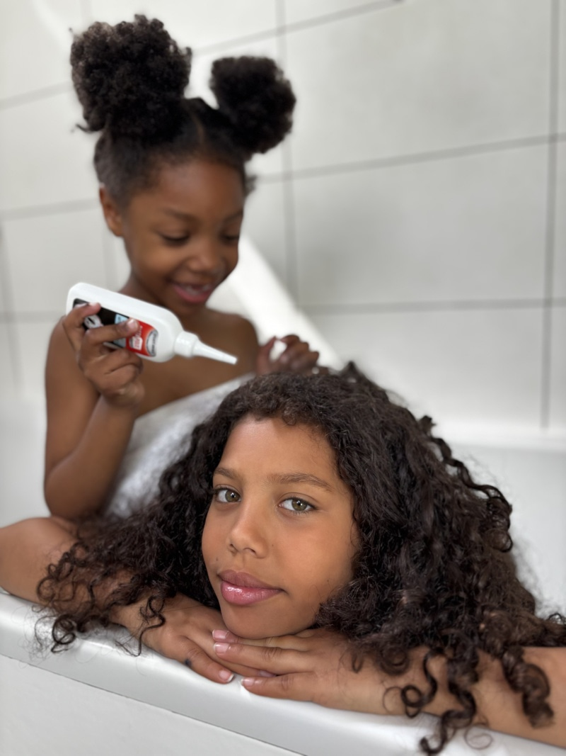 Application d'une lotion anti-poux sur les cheveux d'une enfant
